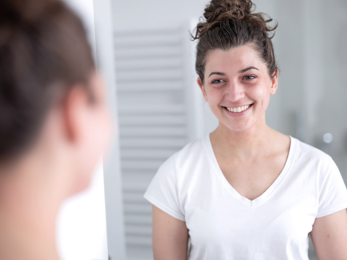 Eine Frau lächelt sich selbst im Spiegel an