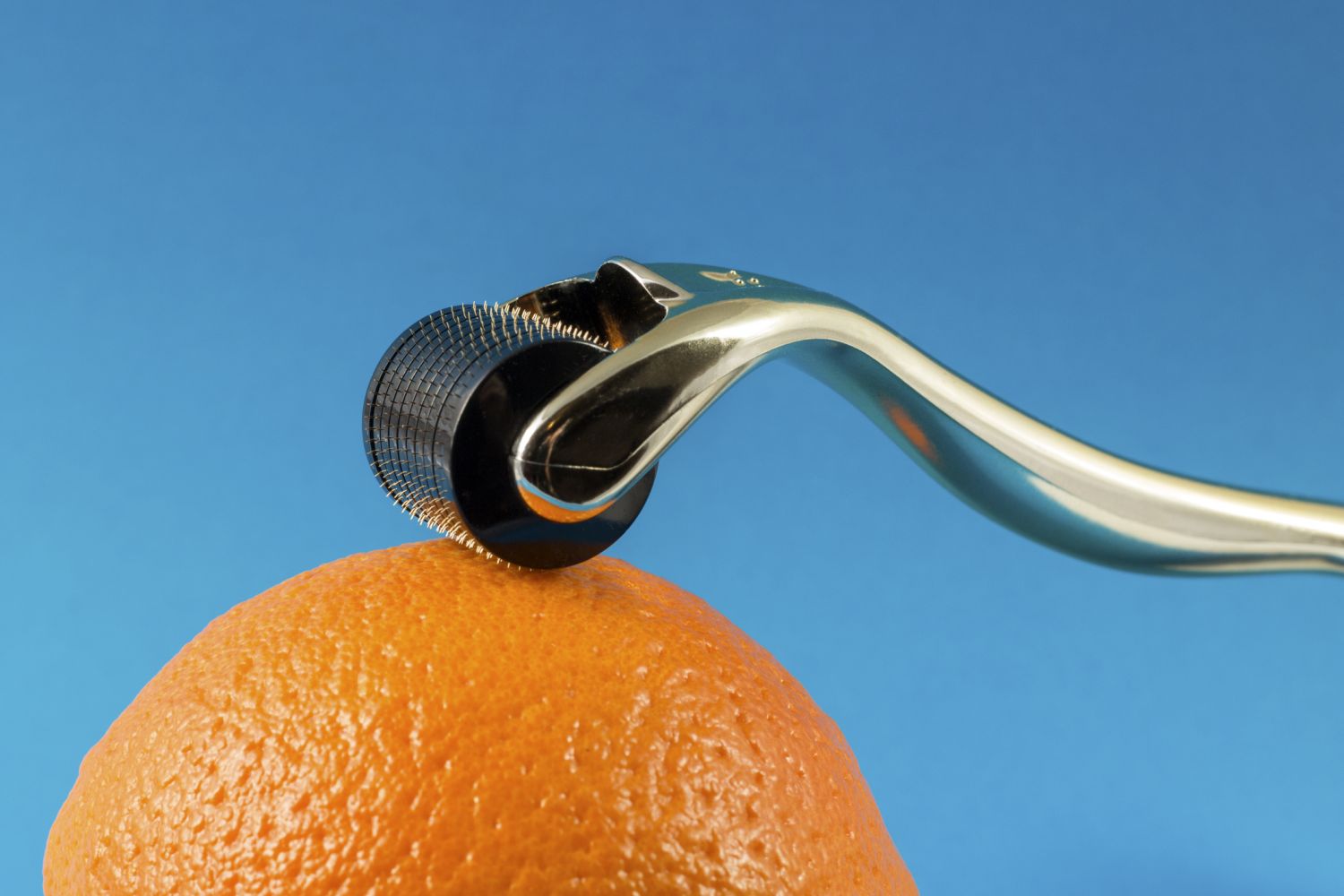 Microneedling-Roller auf einer Orange. Thema: Mittel gegen Cellulite
