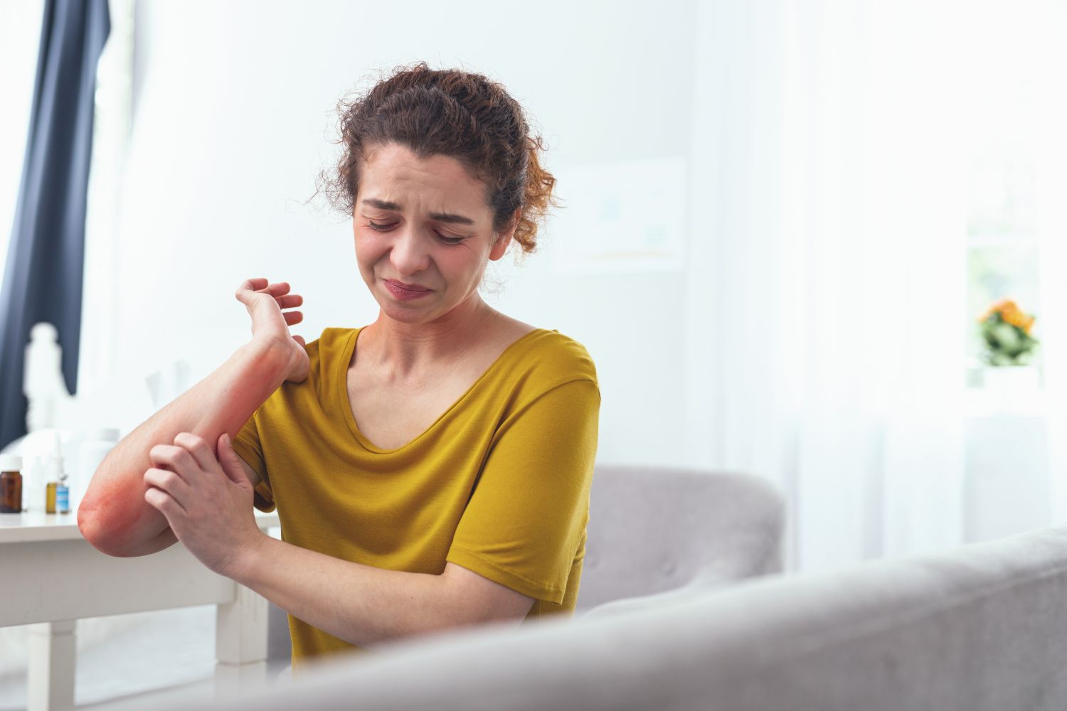 Frau mit Neurodermitis kratzt sich am geröteten Arm. Thema: Neurodermitis-Behandlung